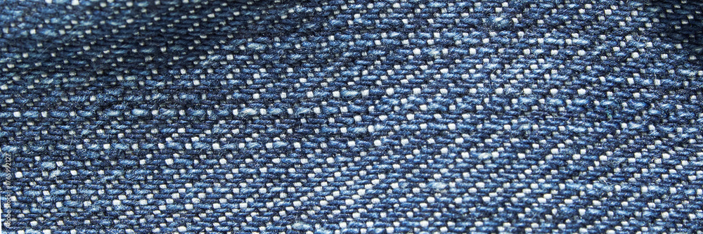 Fototapeta premium Close-up of blue denim fabric texture showing detailed weave pattern in natural light.