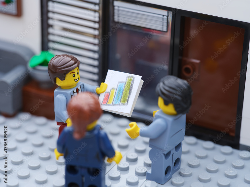 Naklejka premium Tambov, Russian Federation - October 23, 2025 Happy Lego businesspeople minifigures having a meeting and discussing graphs showing the results of their successful teamwork.