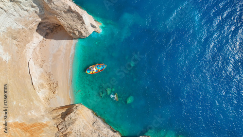 Aerial drone photo of traditional fishing boat anchored in beautiful sea caves with turquoise crystal clear sea and volcanic landscape a true paradise of Zakinthos island, Ionian, Greece