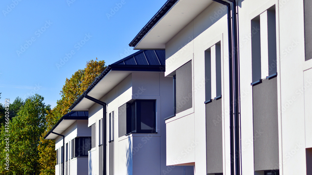 Fototapeta premium Harmony with nature, eco architecture. Terraced single family homes in newly developed housing estate. The real estate market in the suburbs with lush greenery surrounding. 