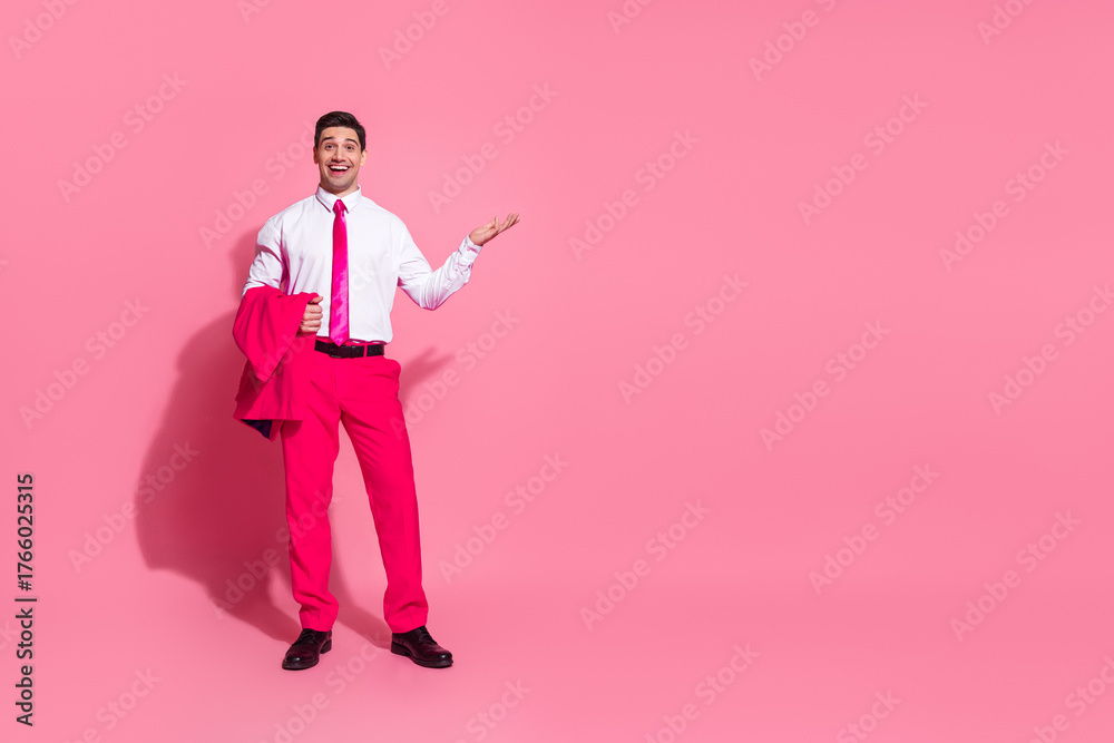 Obraz premium Confident young man in bright pink suit and tie posing with charisma against a vibrant pink studio background
