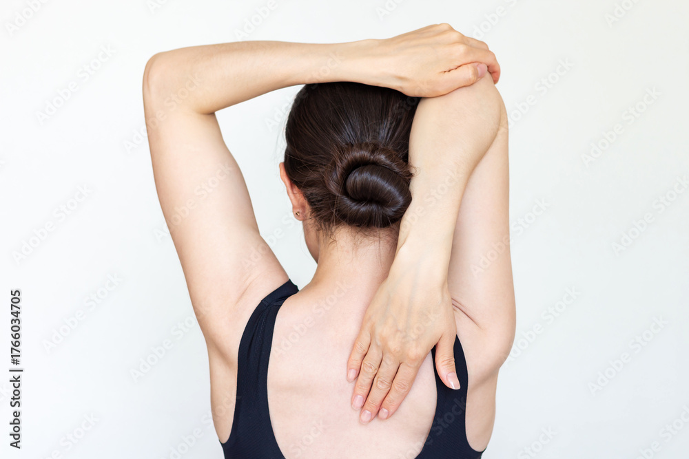 Naklejka premium Young brunette caucasian woman in black clothes doing exercises to strengthen her posture. Rear view