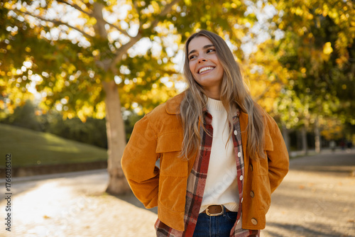 young beautiful blond woman walking in autumn park, stylish , smiling, happy, trendy season warm outfit, wearing velvet terracotta color jacket