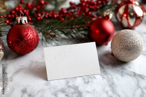Blank Card on a Marble Surface Surrounded by Red and Silver Christmas Ornamen...