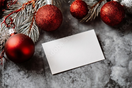 Blank Card on a Marble Surface Surrounded by Red and Silver Christmas Ornamen...