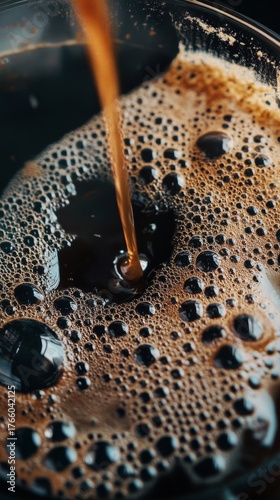 Coffee Pours Into a Black Cup Creating Bubbles and a Rich Texture in a Cozy S...