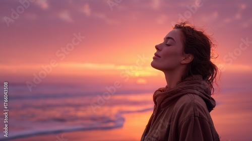 Peaceful woman inhaling deeply during a colorful sunset on the beach
