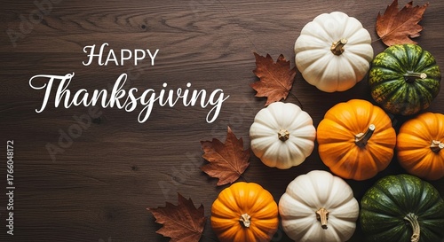 Thanksgiving greeting with pumpkins and autumn leaves arranged on a wooden surface.