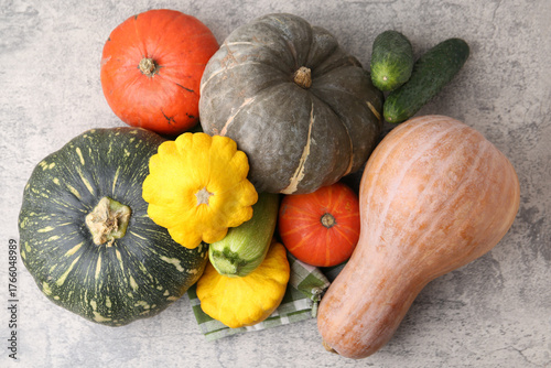 Many fresh pumpkins and other vegetables of gourd family on light grey textured table, flat lay © New Africa
