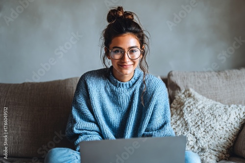 Young Woman Smiles While Working on Laptop at Home in Cozy Living Room During...