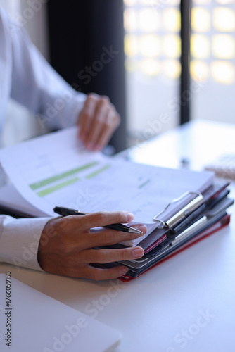Businessman working in office reading, signing stack of documents.