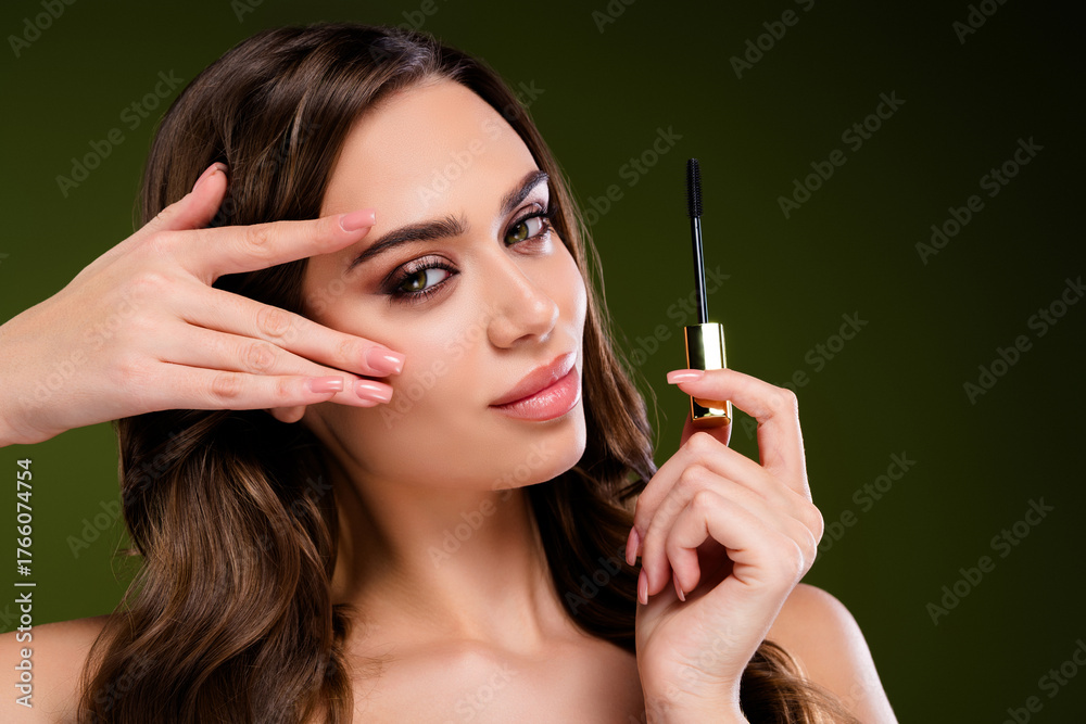 Fototapeta premium Attractive brunette woman showcasing makeup application with elegant glamour and style on green background.