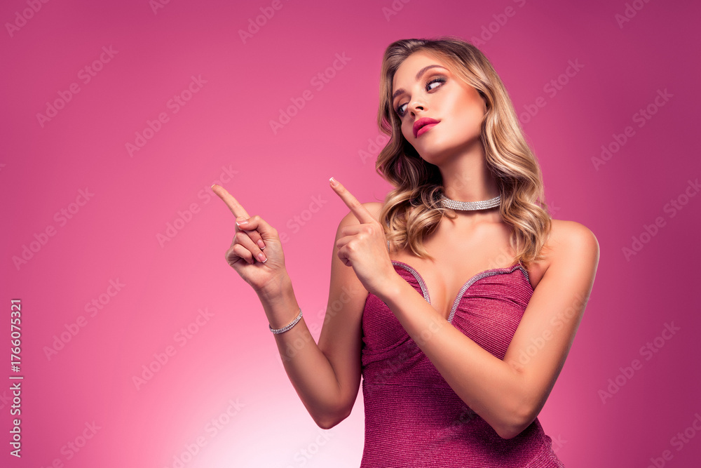 Obraz premium Luxurious young woman in a stylish pink dress posing against a vibrant pink background, exuding charm