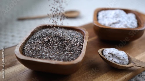 Nutritious chia seeds pouring into a rustic wooden bowl next to a serving of delicious chia pudding on a spoon, showcasing a healthy superfood breakfast preparation in a natural setting