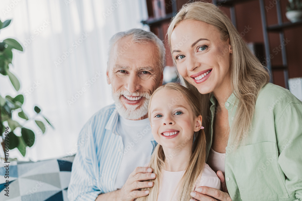 Obraz premium Warm family moment with grandma mom and daughter smiling together at home in a cozy living room with plants and shelves