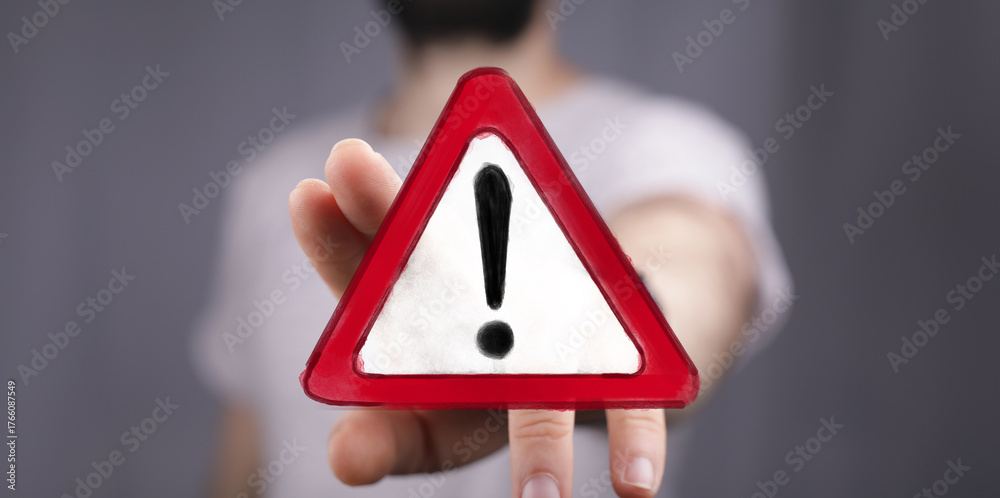 Fototapeta premium High-impact image of a hand presenting a warning sign. Perfect for conveying urgency, risk, and attention.