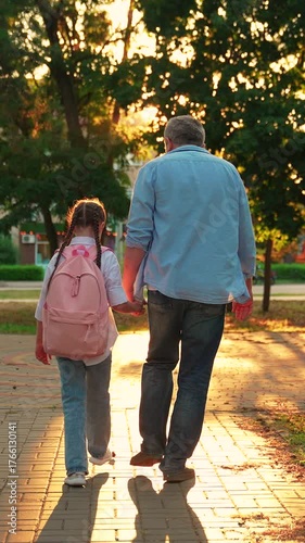 Dad walks kid with backpack to school for classes along city street. Parent father, child daughter walk to school together. Happy family. Dad child rearing concept. Family city park. People education