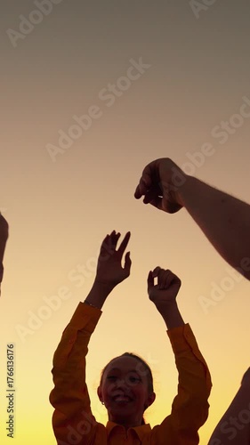 Girls boy having fun outdoors, dancing on beach, relaxing in nature. Party dancing, group of happy people raising their hands to sky in evening. People dancing to music concert, raising their hands up