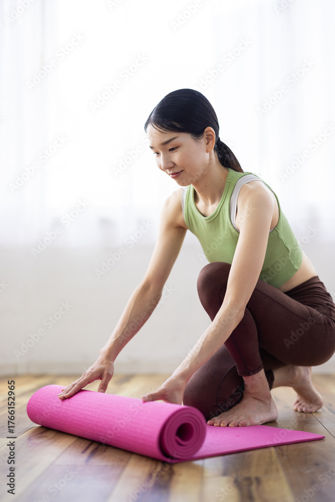 Fototapeta premium Asian Woman Preparing Yoga Mat at Home in Natural Light