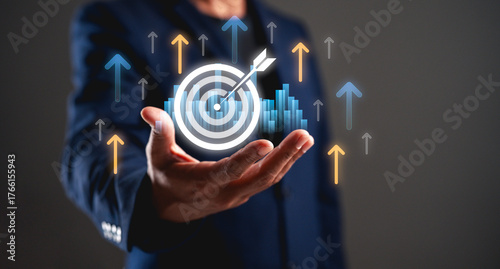 A businessman presents a digital target graphic with upward arrows, symbolizing growth, success, and achievement in a professional setting.