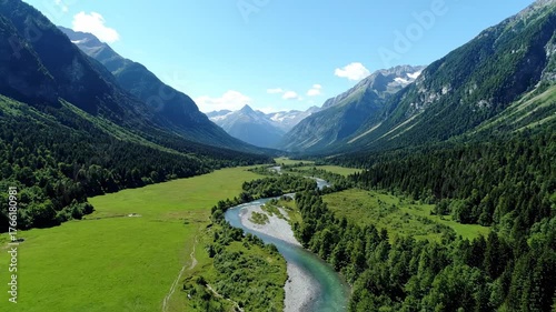 A magnificent sweeping aerial drone shot showcasing a winding river gracefully flowing through a vast, pristine green mountain valley freedom, gracefully, water