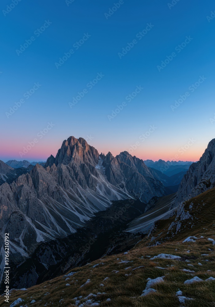 Fototapeta premium Serene mountain landscape at dusk, showcasing rugged peaks, deep valleys, and the transition from warm sunset colors to cool, peaceful blue twilight ,summit ,scenic ,blue