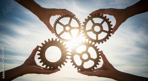 Four hands connect interlocking wooden gears against a vibrant sunlit sky, powerfully symbolizing effective teamwork, collaboration, and collective problem-solving for shared growth and success