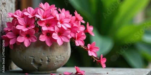 A Delicate Arrangement of Vibrant Pink Blossoms in a Rustic Stone Pot, Gracefully Cascading and adding a Touch of Natural Beauty to a Serene Outdoor Setting