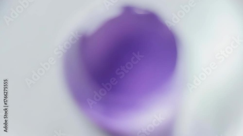 A purple, gel-like substance inside a curved, white container