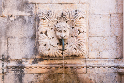 Dubrovnik fountain sculpture streaming water from stone face