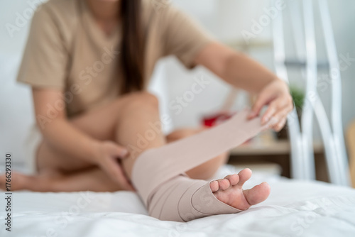 Close up of injured woman wearing splint on leg in cozy bedroom at home.
