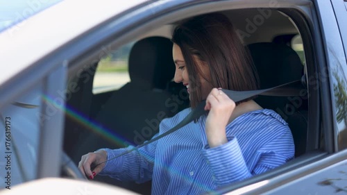 Smiling young woman getting into her car and fastening her seat belt. Important safety measure for responsible driving and accident prevention