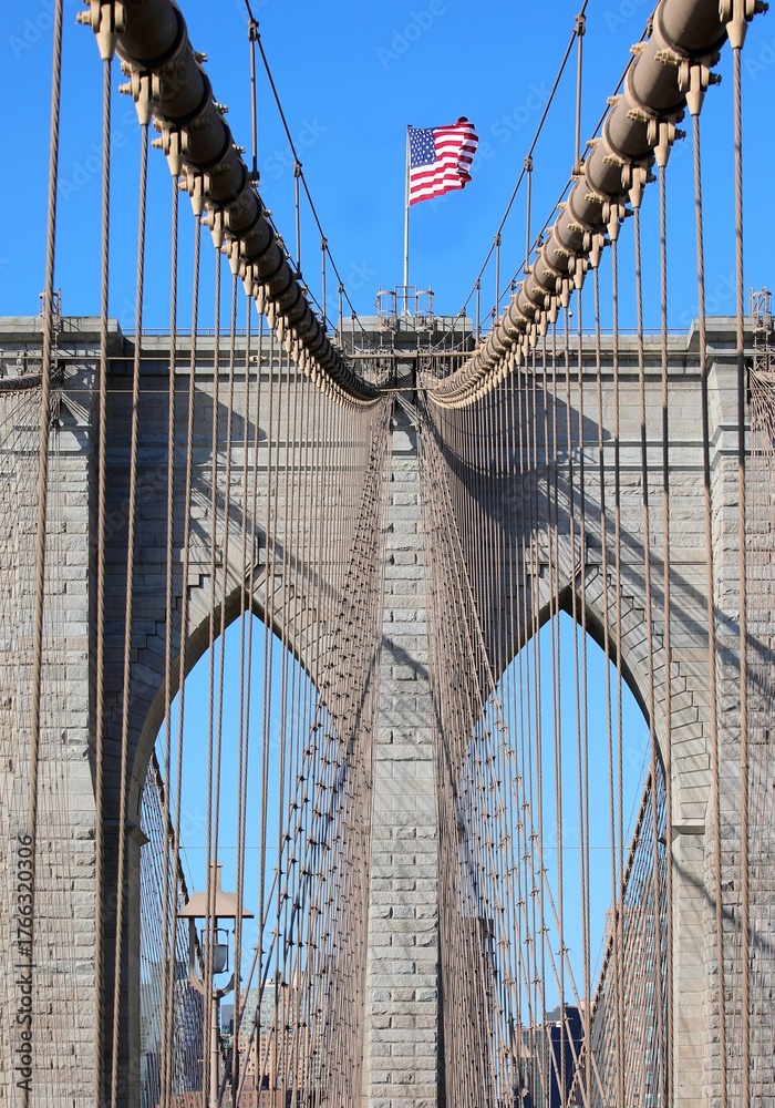 Fototapeta premium Brooklyn Bridge with American Waving Flag on top of Tower and blue sky