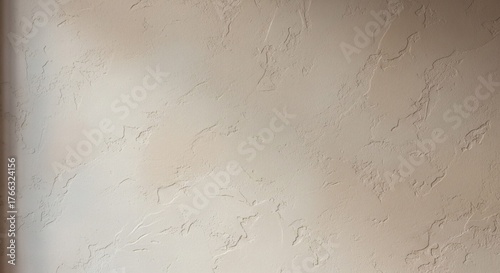 Detailed view of a light beige decorative plaster wall with a rough, whisked texture, showcasing an elegant and artisanal surface for backgrounds