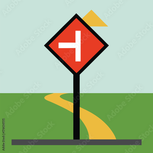 Road intersection warning sign with a yellow road curving into a t junction against a pale blue sky and green grass background