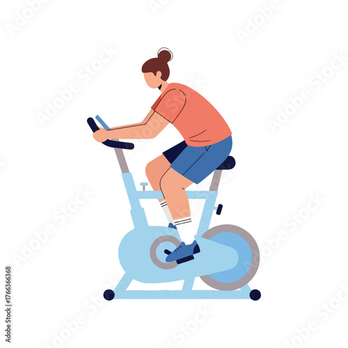 Energetic woman with brown hair in a bun, wearing a coral t-shirt and blue shorts, exercising on a light blue stationary bicycle