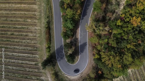 Curva strada in campagna, tornante di asfalto auto che percorre una curva vista aerea