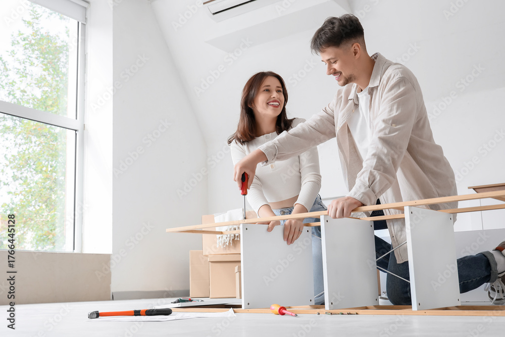 Obraz premium Young couple assembling shelf unit in bedroom on moving day