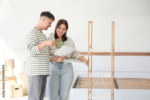 Young couple with instructions assembling shelving unit in bedroom on moving day
