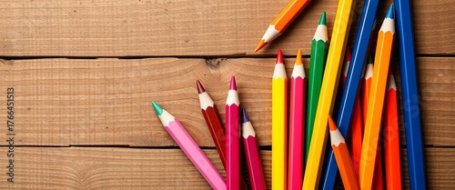 Assorted color pencils scattered on a textured wooden background, school supplies, back to school