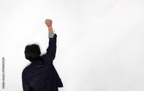 Фотография Raised fist with red and white ribbon (Indonesia flag colors) symbolizing spirit, struggle, and patriotism, against a bright white background with copy space