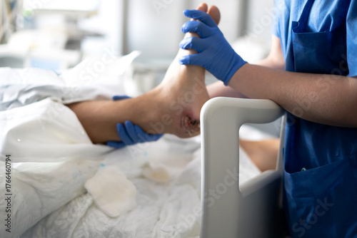 Nurse examining patient foot wound in hospital bed