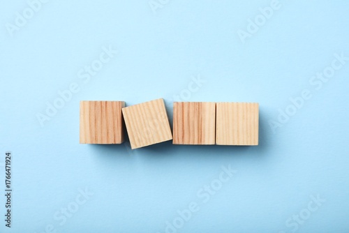 Wooden cubes on light blue background, top view