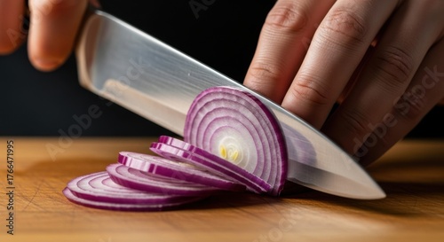 Closeup shot of a chefs hands slicing a red onion with a sharp knife on a wooden cutting board