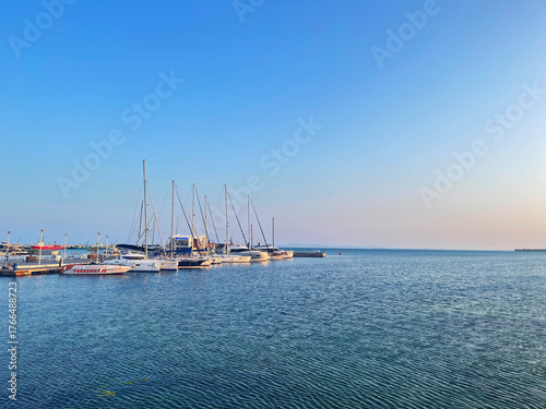 Sailboats docked at the marina under a clear blue sky at sunset