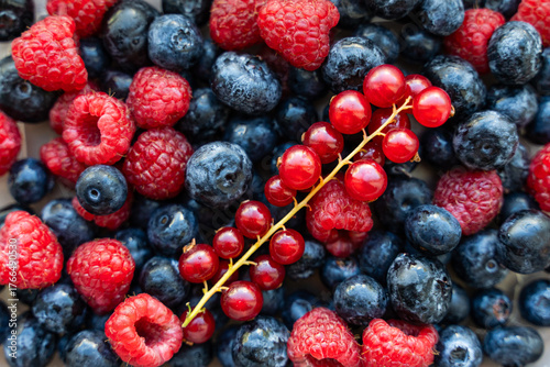 A plate with berries. Blackcurrants, raspberries and blueberries top view.