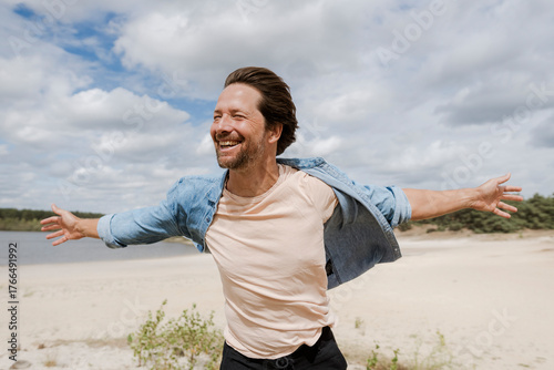 Smiling man with open arms enjoying wind in nature