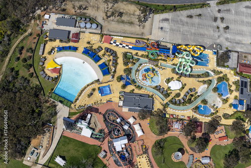 Aerial view of the vibrant Gumbuya World theme park with its water slides, wave pool, and green spaces creating a tapestry of fun and leisure, Tynong North, Victoria, Australia.