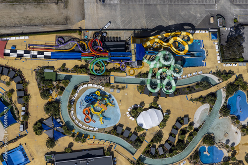 Aerial view of vibrant water slides twisting and turning against the tan landscape of the Gumbuya World theme park, Tynong North, Victoria, Australia.
