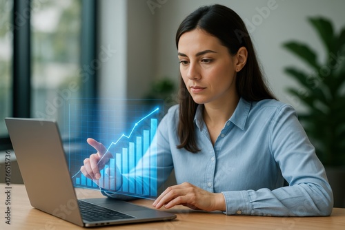 Woman interacting with holographic data chart from laptop